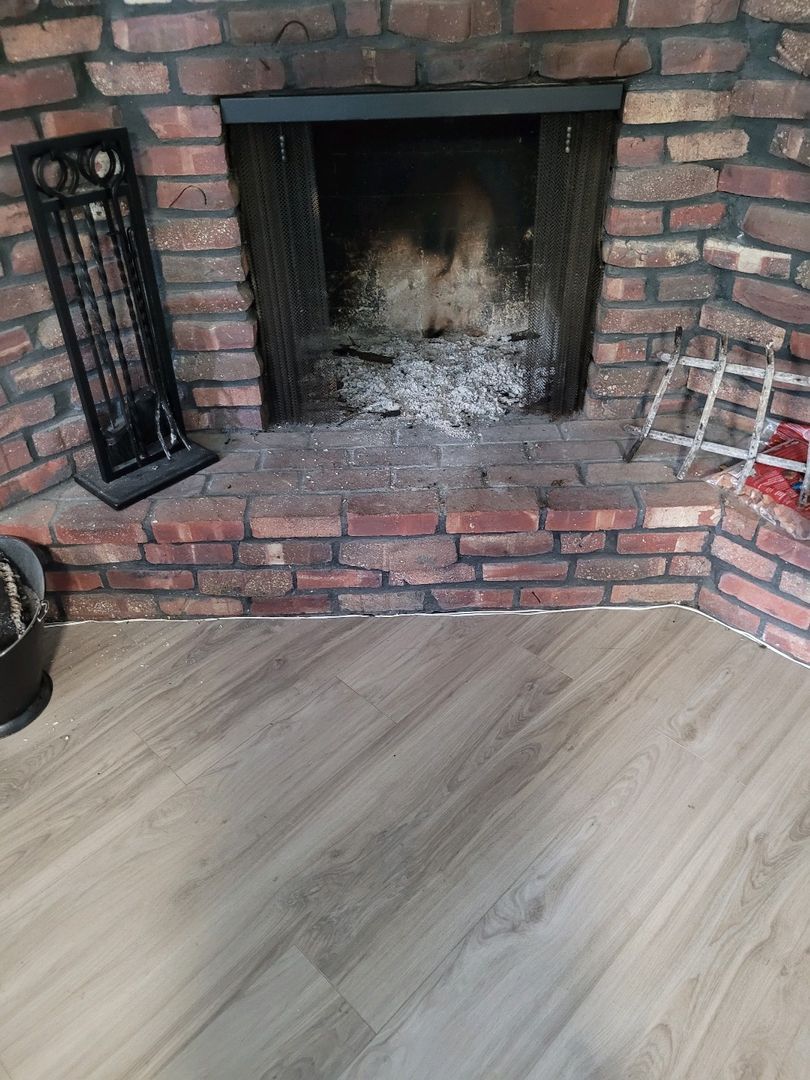 Brick fireplace with ash buildup and accompanying cleaning tools on the side