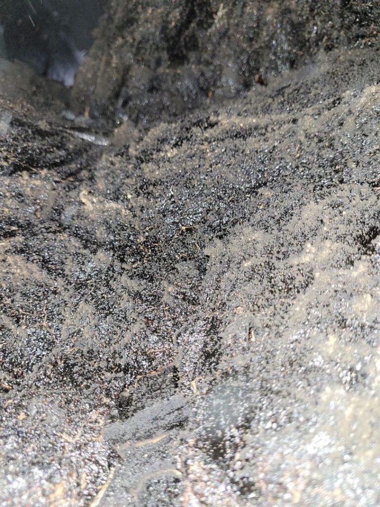 Close-up image of black creosote buildup with a granular texture