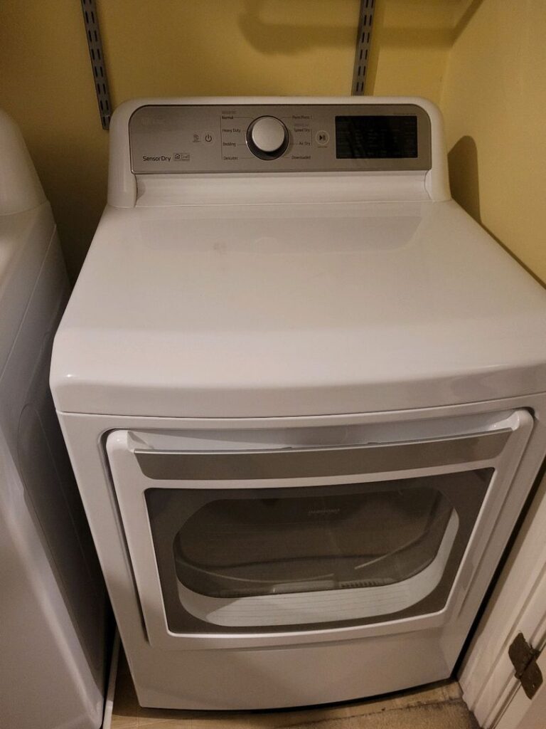 White front-loading clothes dryer with control panel in a laundry room