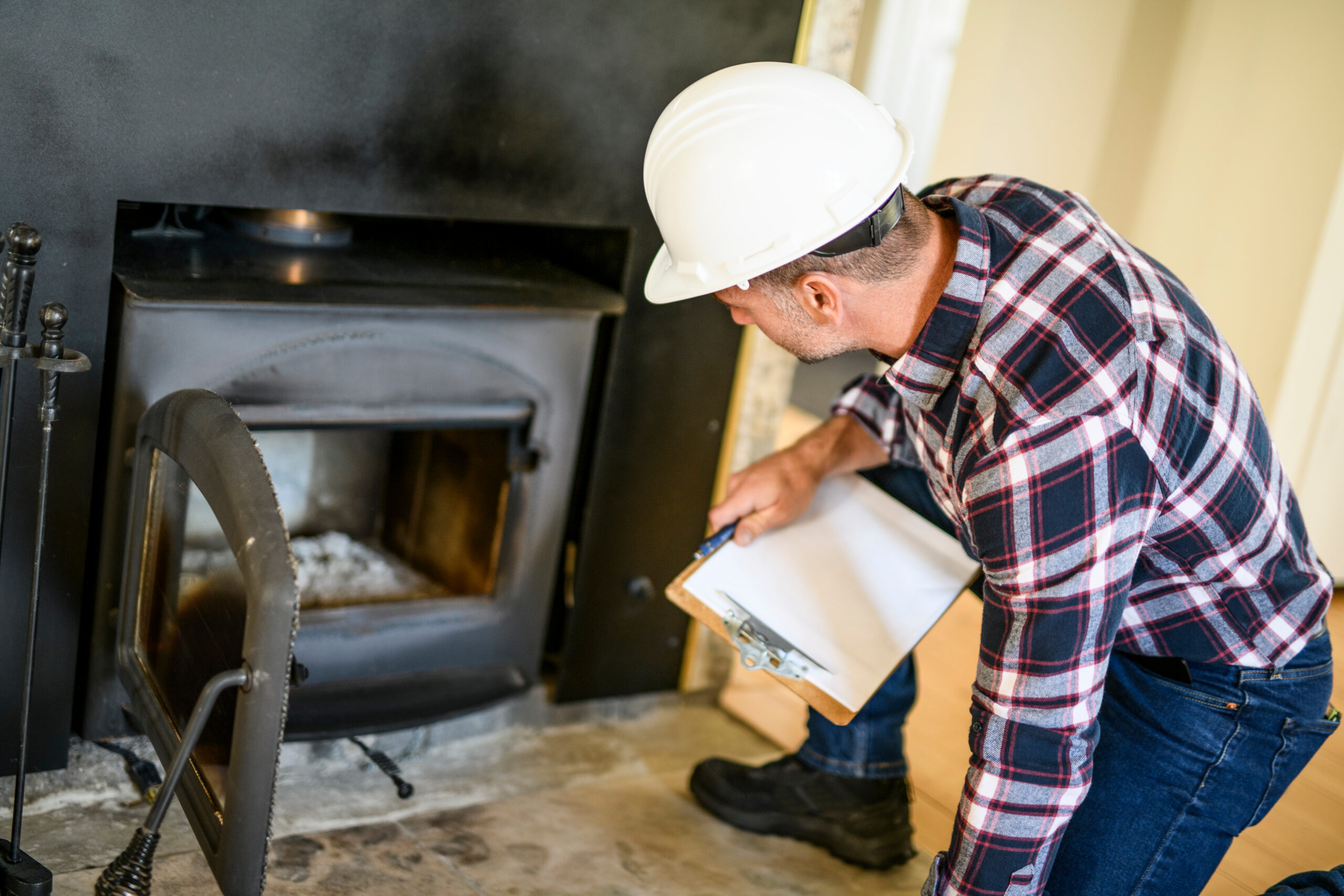 A chimney technician takes a closer look at a fireplace.